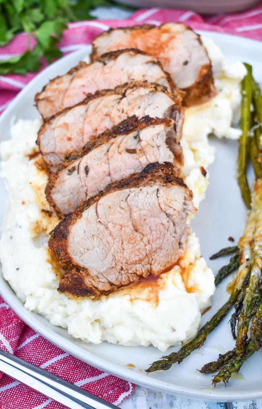 air fryer pork tenderloin cut into slices overtop of mashed potatoes on a gray plate