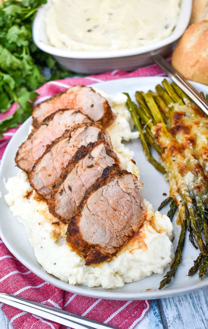 air fryer pork tenderloin cut into slices overtop of mashed potatoes on a gray plate
