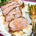 air fryer pork tenderloin cut into slices overtop of mashed potatoes on a gray plate