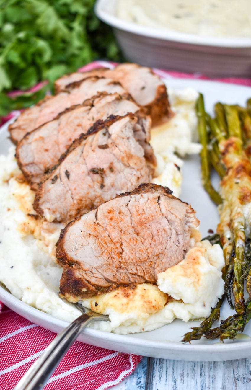 air fryer pork tenderloin cut into slices overtop of mashed potatoes on a gray plate