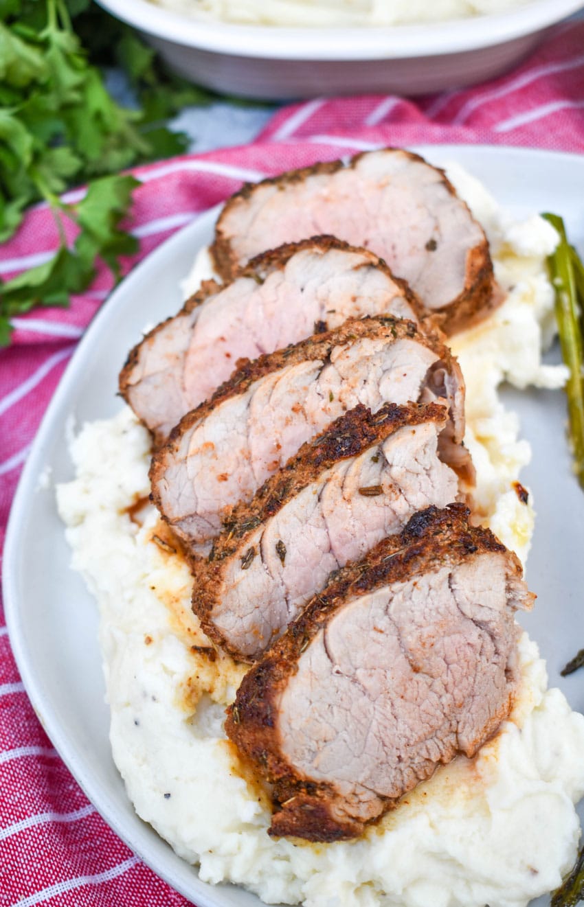air fryer pork tenderloin cut into slices overtop of mashed potatoes on a gray plate