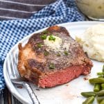 a cut air fried steak on a white dinner plate with a silver fork on the side