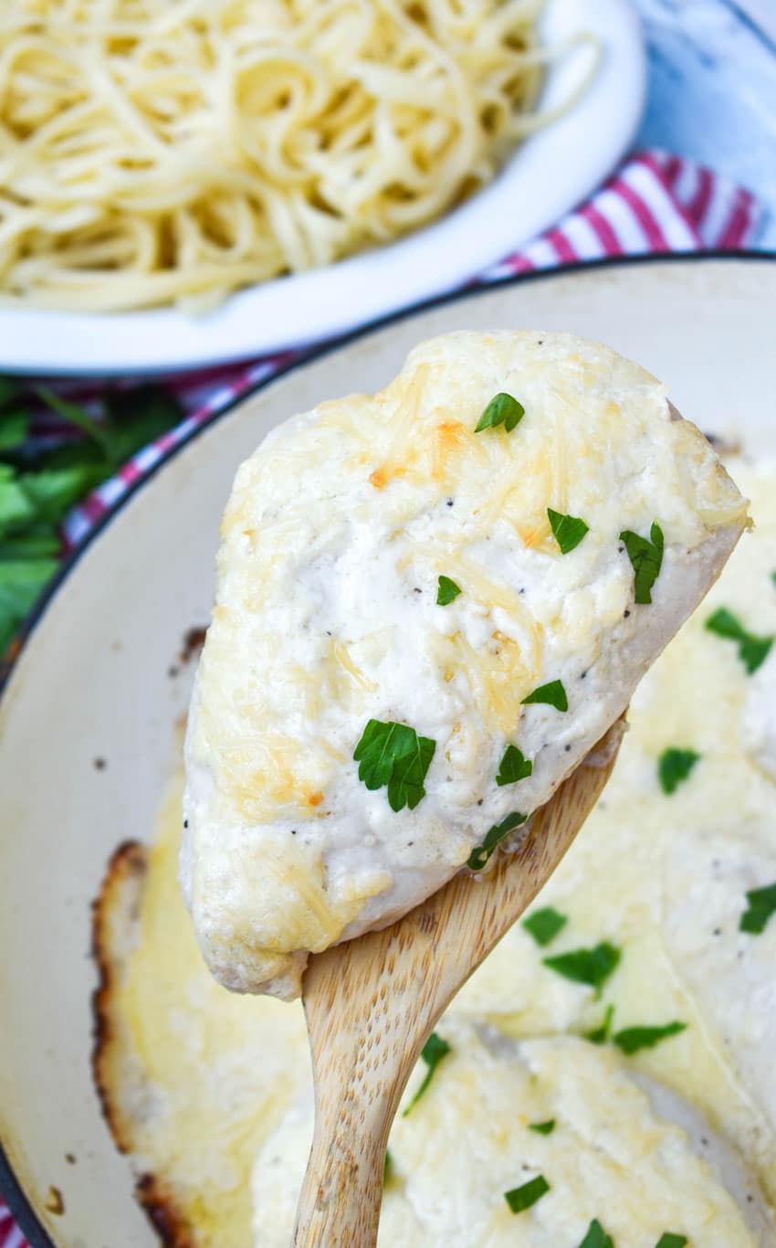 a wooden spatula holding up a piece of creamy caesar chicken