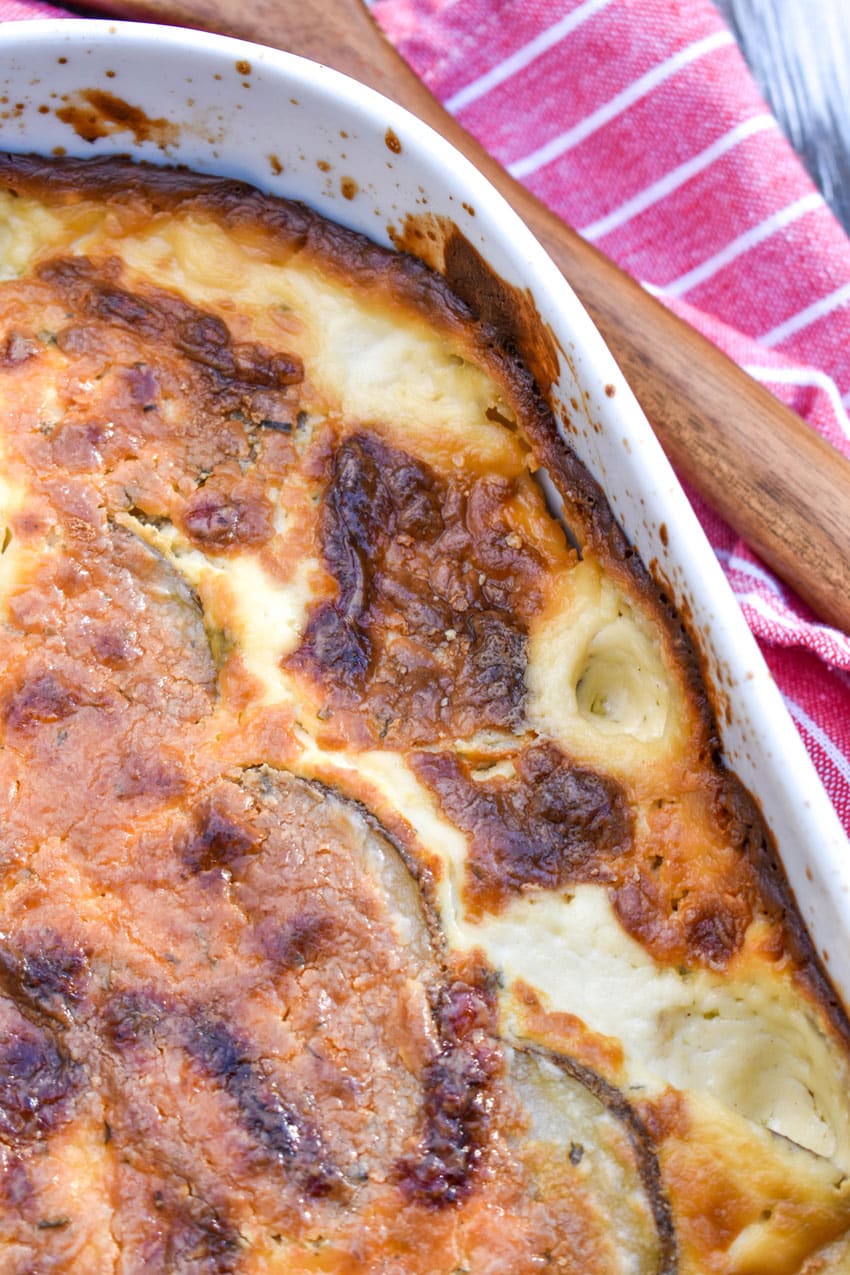 creamy scalloped potatoes with boursin cheese in a large white casserole dish