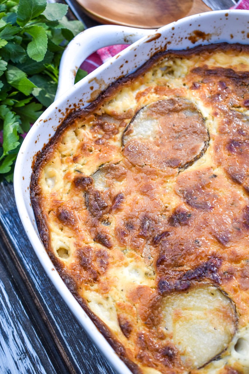 creamy scalloped potatoes with boursin cheese in a large white casserole dish
