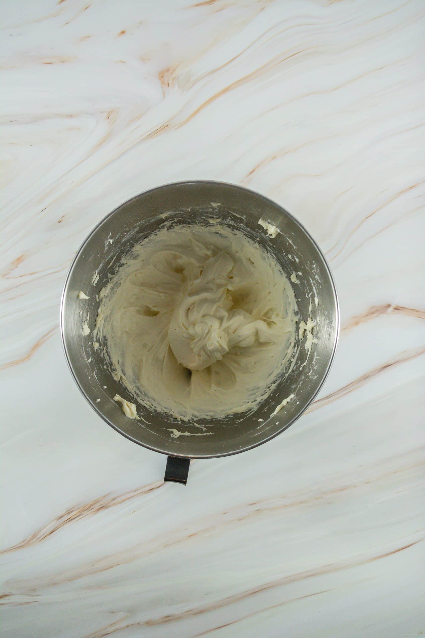 vanilla frosting on a metal mixing bowl