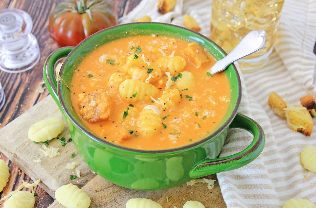 instant pot tomato soup with gnocchi in a green bowl with a silver spoon on the side