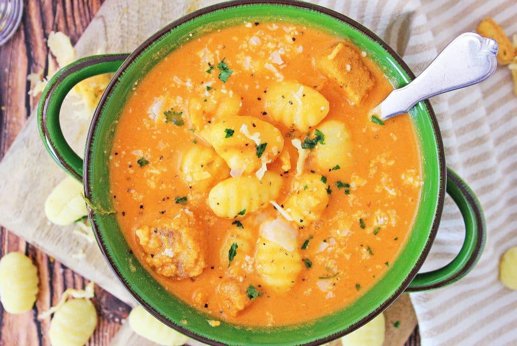 instant pot tomato soup with gnocchi in a green bowl with a silver spoon on the side