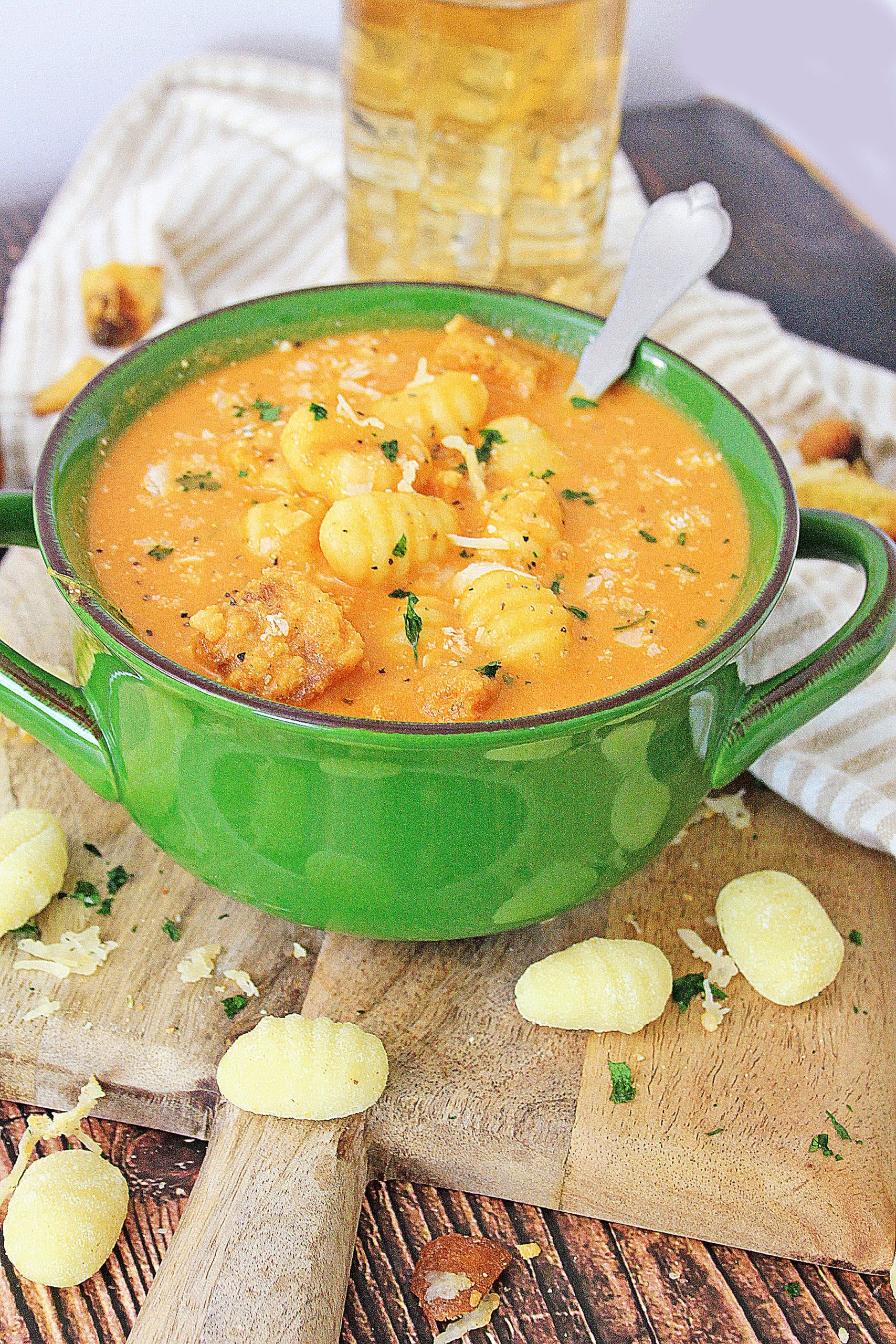 instant pot tomato soup with gnocchi in a green bowl with a silver spoon on the side