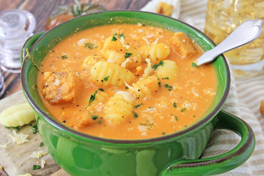 instant pot tomato soup with gnocchi in a green bowl with a silver spoon on the side