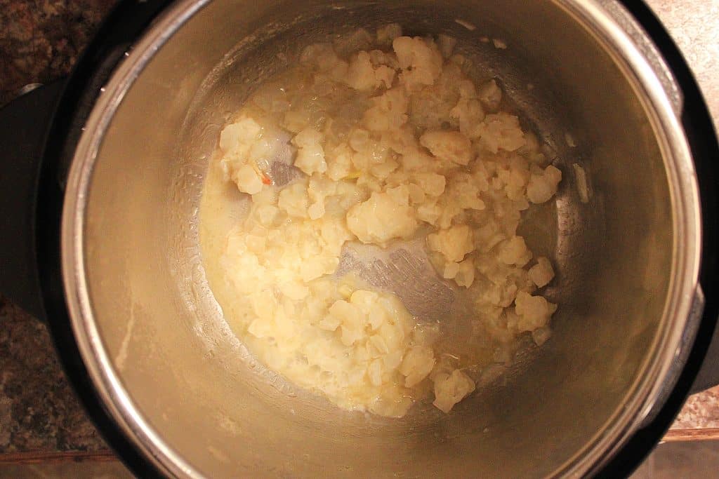 diced onions in butter sauteing in the bowl of an instant pot