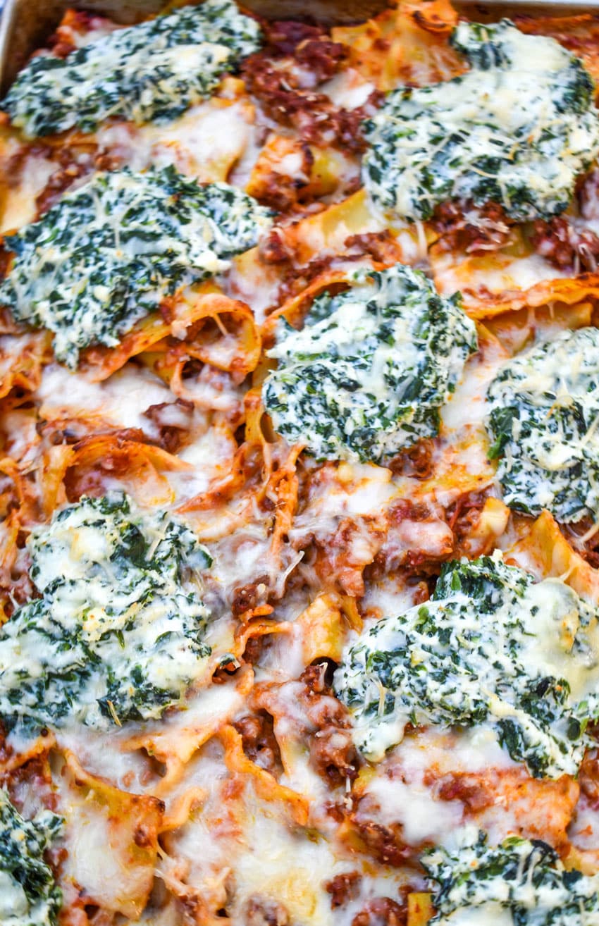 a close up of ricotta cheese and spinach topped sheet pan lasagna on a metal baking sheet