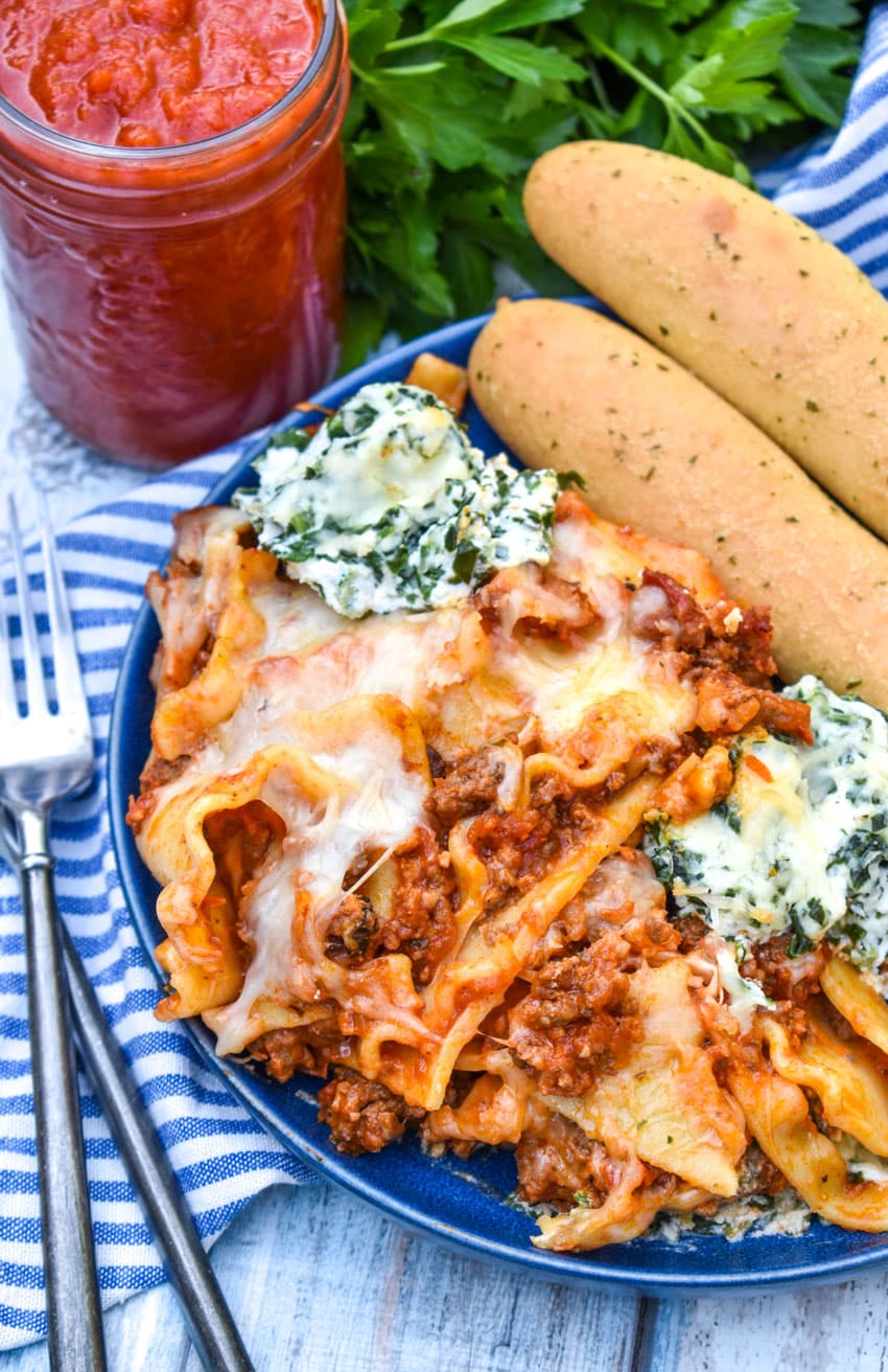 Sheet Pan Lasagna sheet pan lasagna shown on a blue plate with two breadsticks on the side