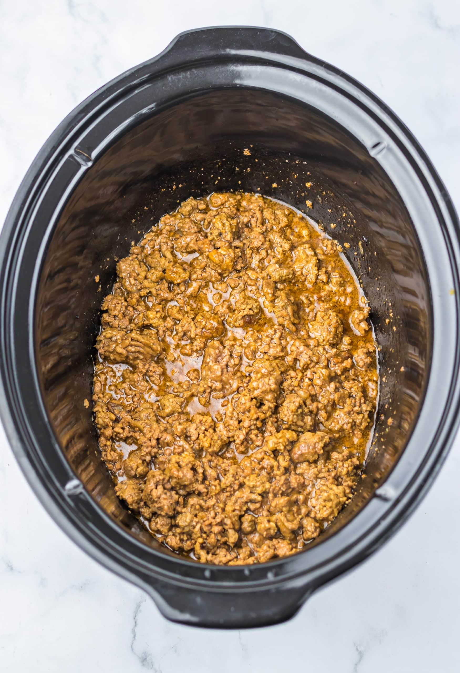 sauced ground beef mixture in the black bowl of a slow cooker