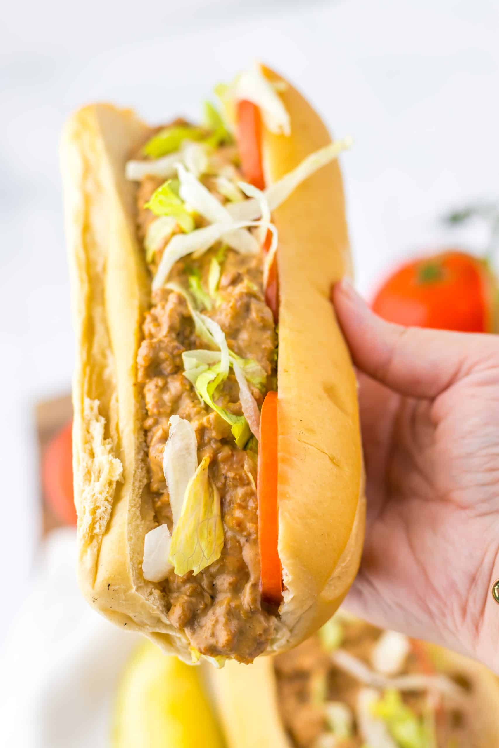 a hand holding up a chopped cheese sub sandwich