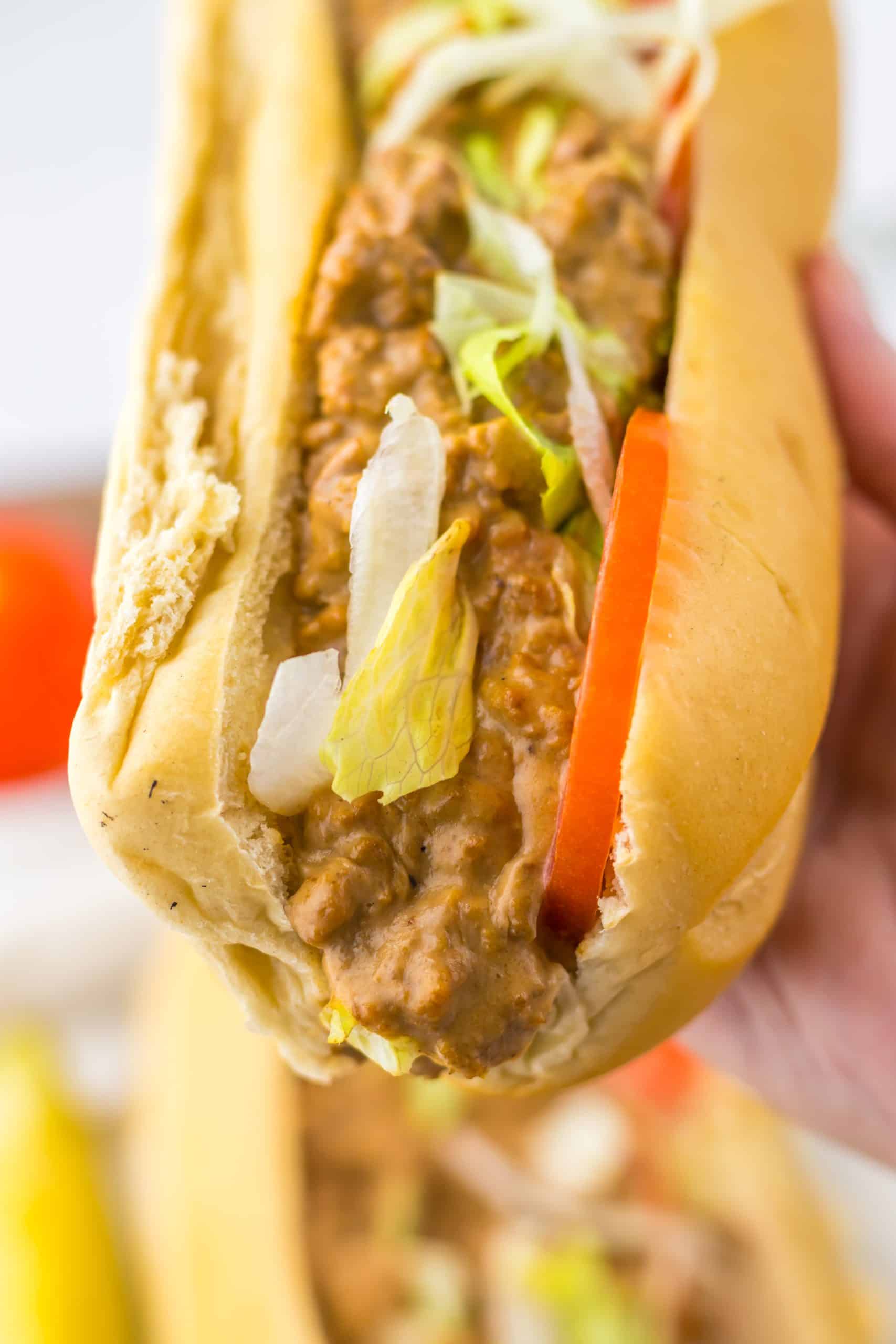 a hand holding up a chopped cheese sub sandwich