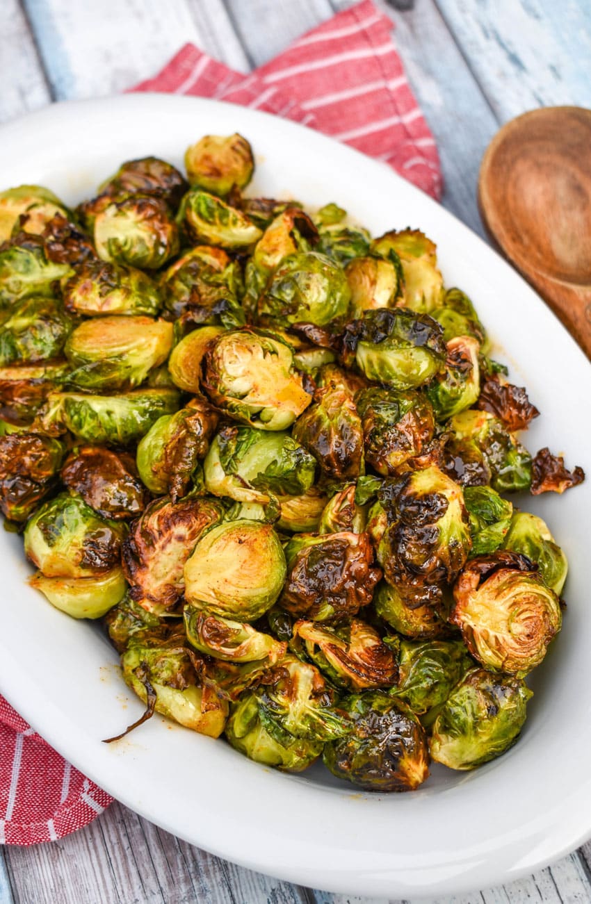 air fryer brussels sprouts in a white serving dish on top of a red cloth napkin