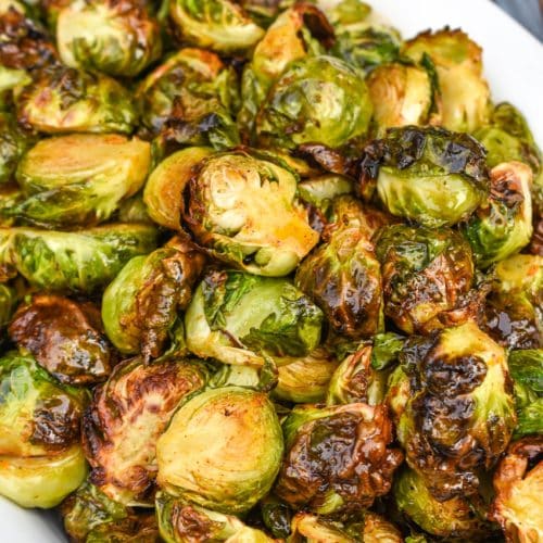 air fryer brussels sprouts in a white serving dish on top of a red cloth napkin