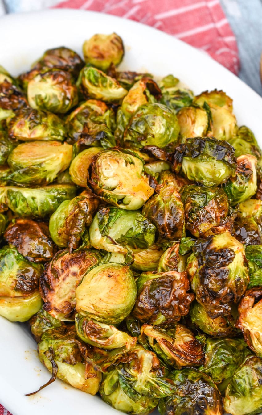 air fryer brussels sprouts in a white serving dish on top of a red cloth napkin