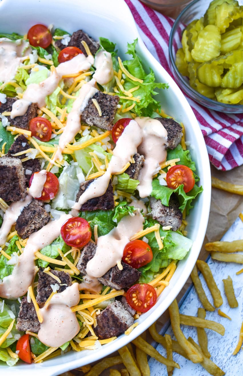 big mac salad with thousand island dressing in a large white serving bowl