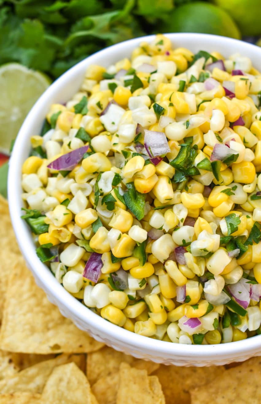 fresh corn salsa recipe in a white bowl surrounded by tortilla chips