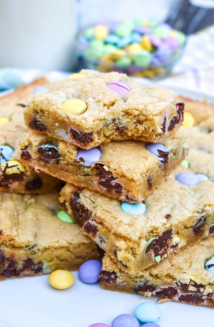 cut squares Easter cookie bars stacked on a white plate with a bite taken out of the corner of the top slice