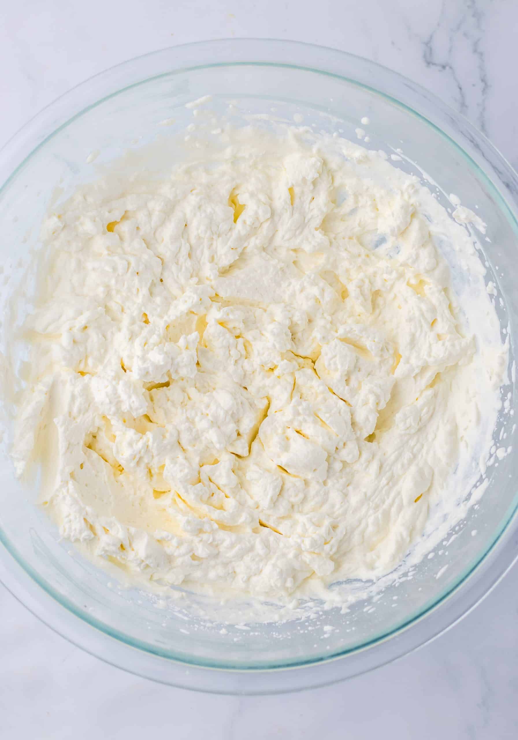 stabilized whipped cream with stiff peaks in a large glass mixing bowl