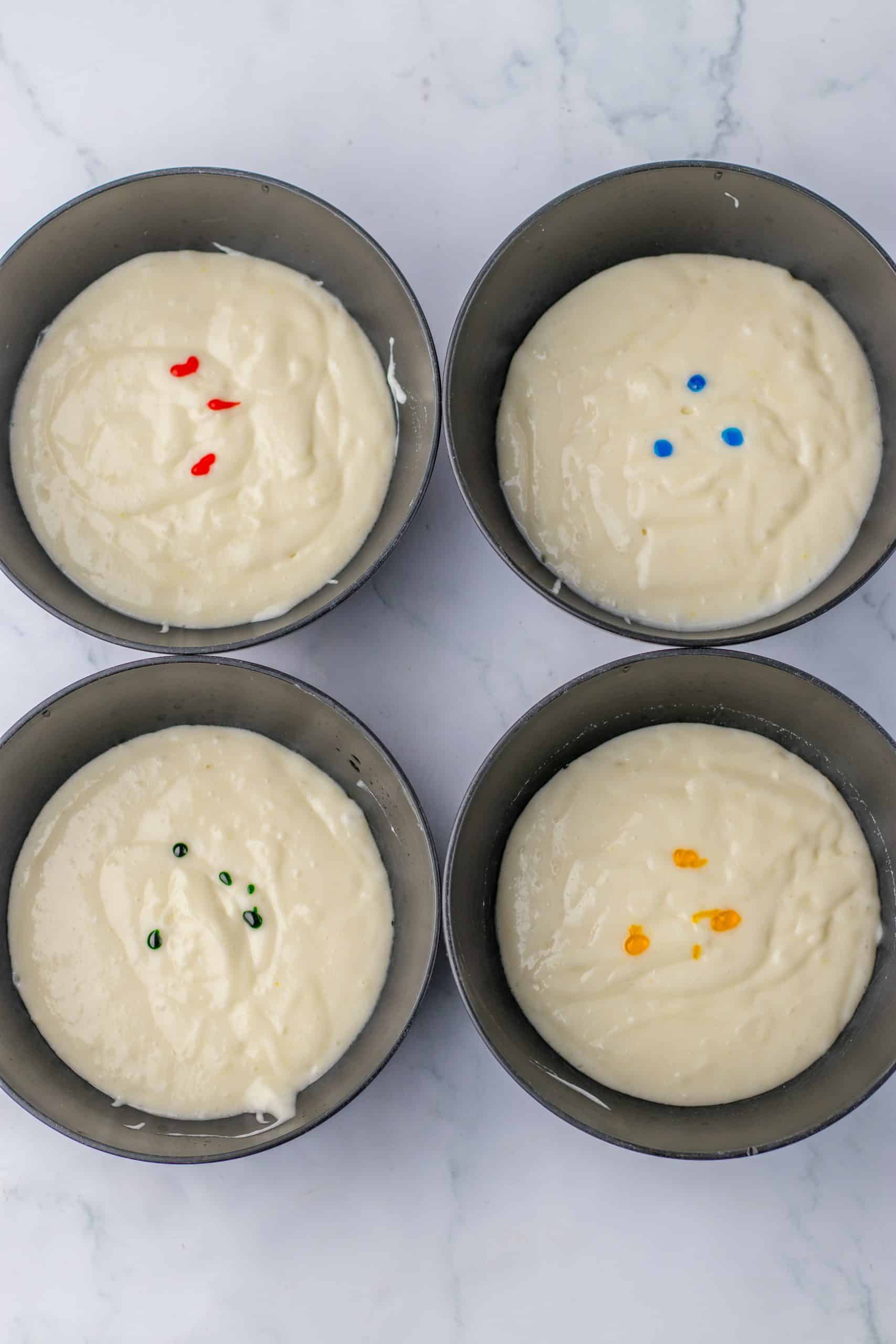 four cake pans filled with cake batter