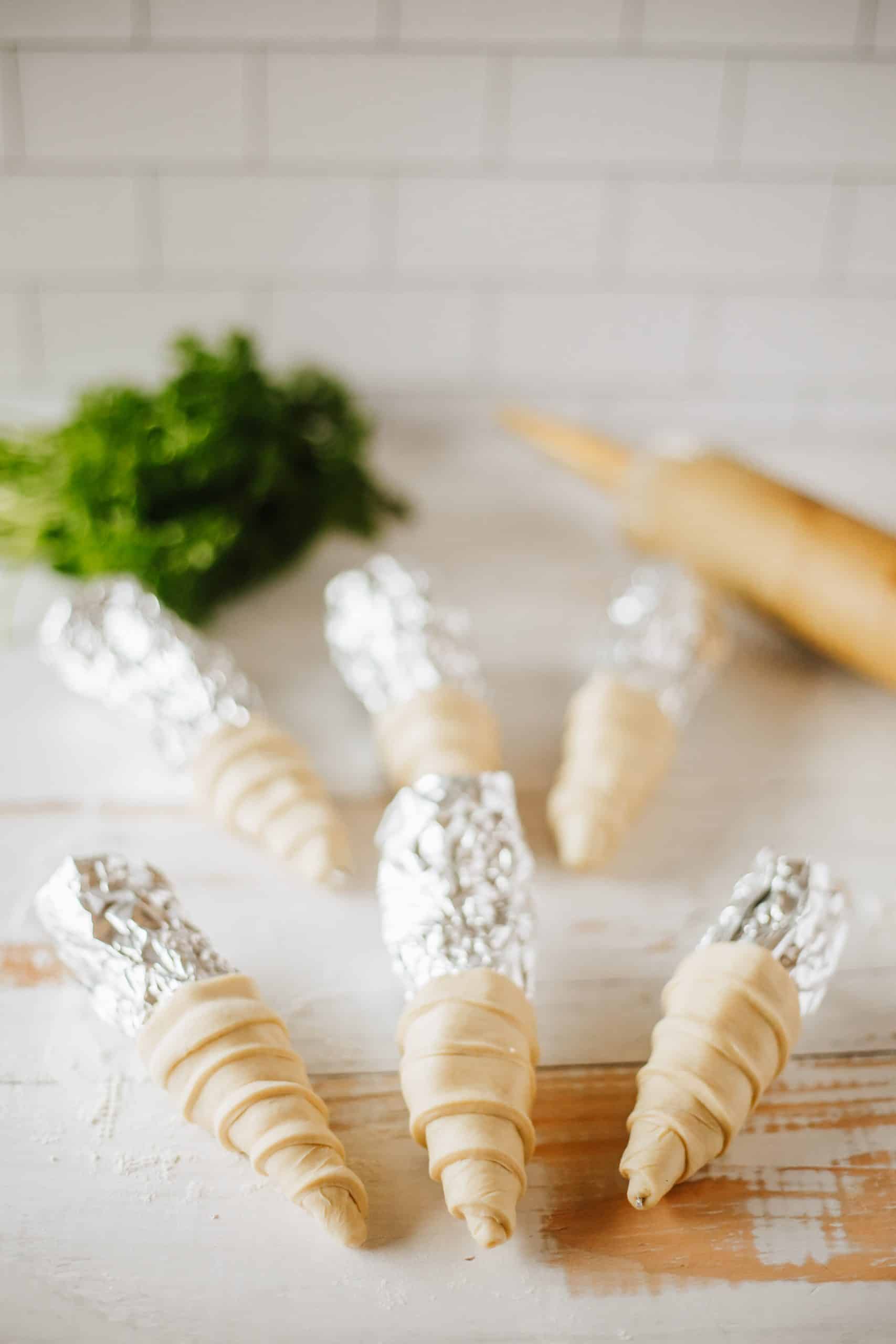 crescent rolls wrapped around aluminum foil to form a carrot shape