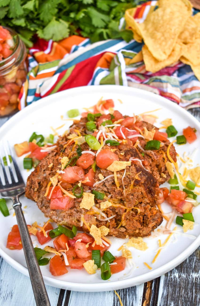 slices of mexican meatloaf on a white plate with a silver fork on the side