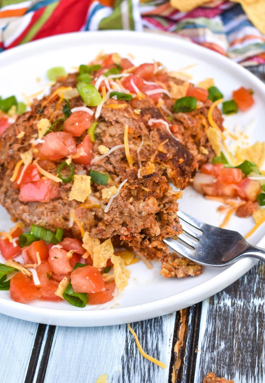 slices of mexican meatloaf on a white plate with a silver fork on the side