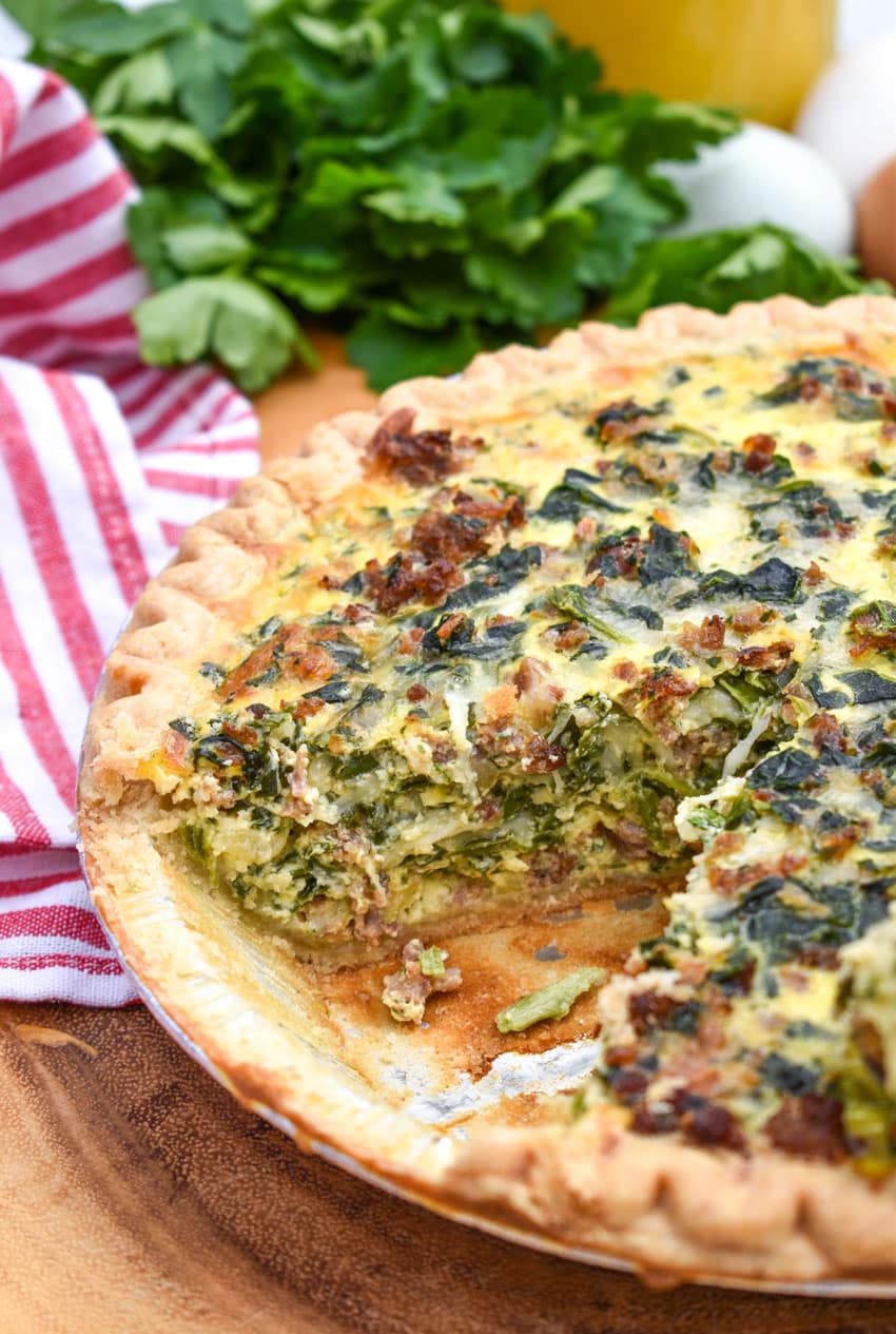 a sausage and spinach quiche with a slice removed to show the filling