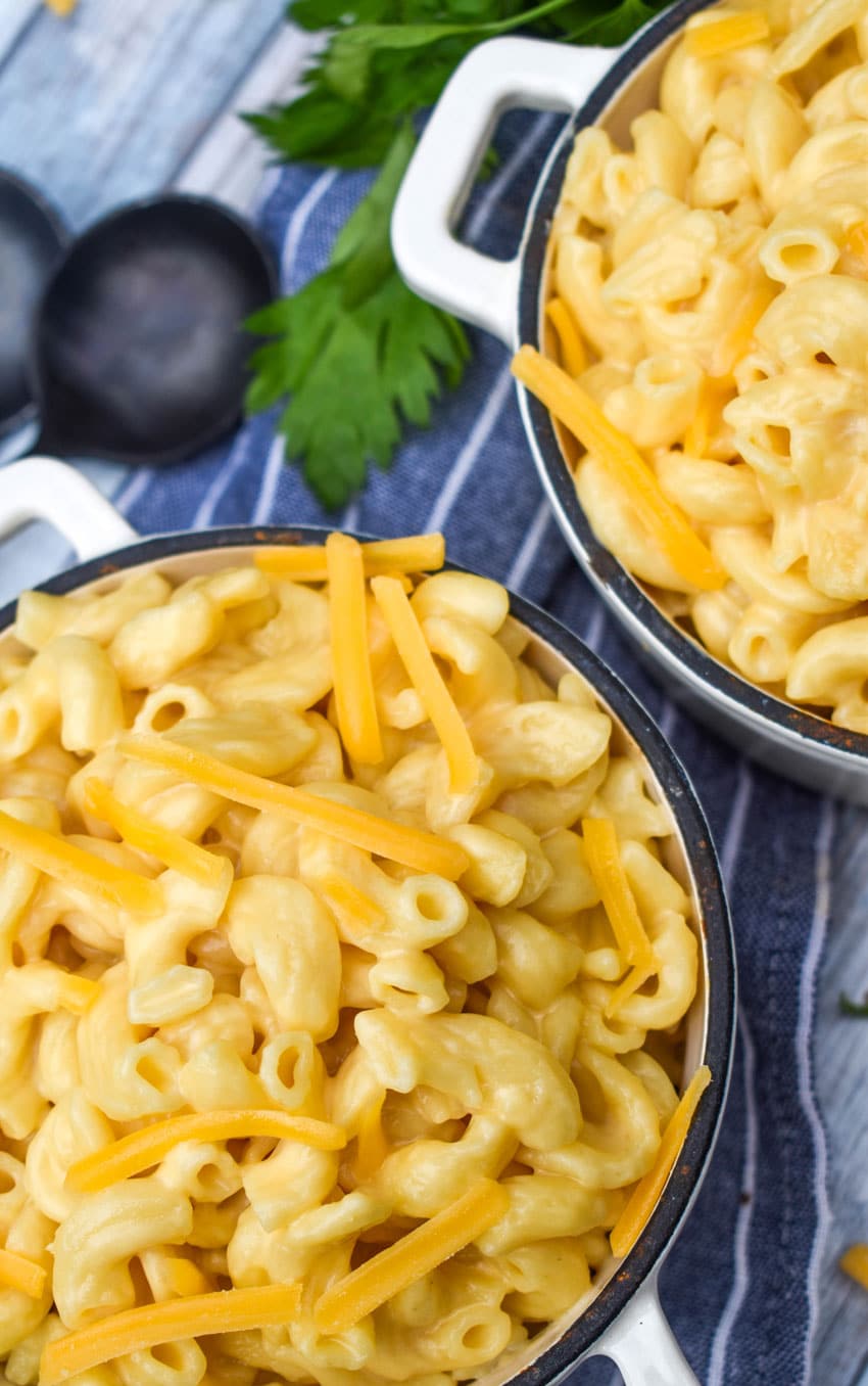 instant pot mac and cheese in two cast iron bowls topped with shredded cheddar cheese