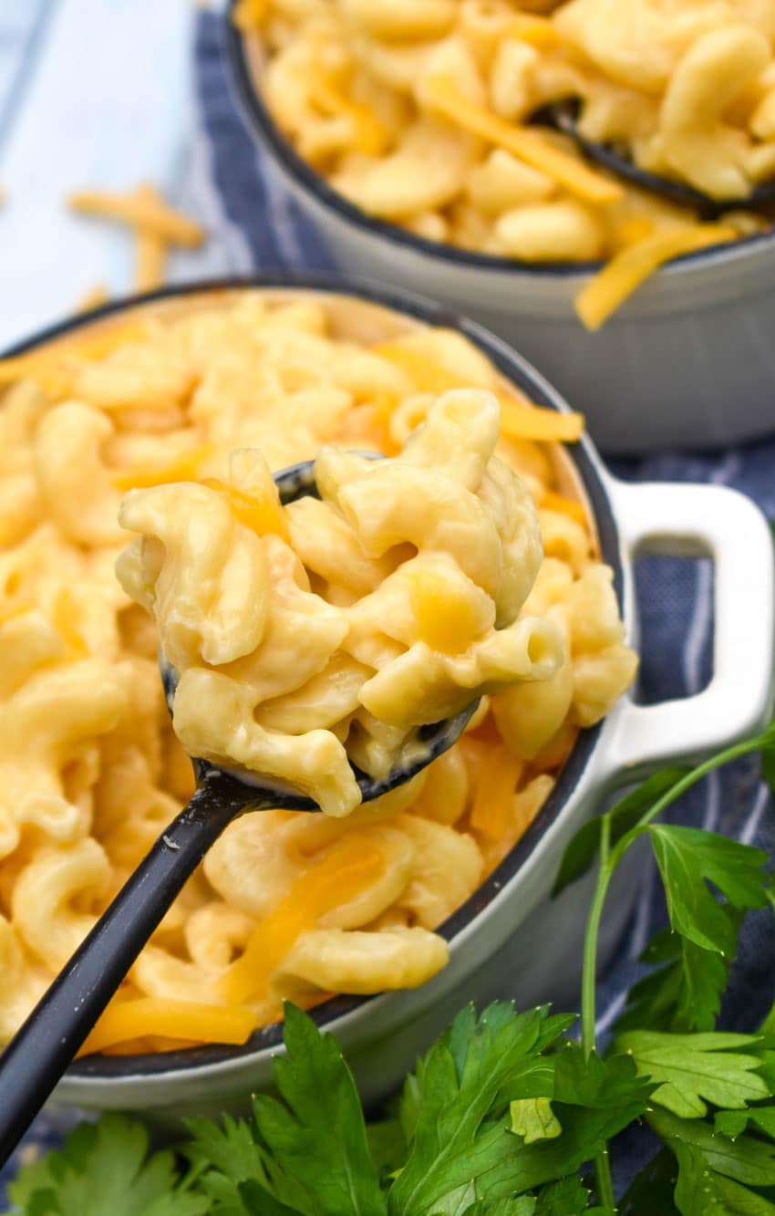a black spoon holding up a scoop of extra creamy mac and cheese made in an instant pot