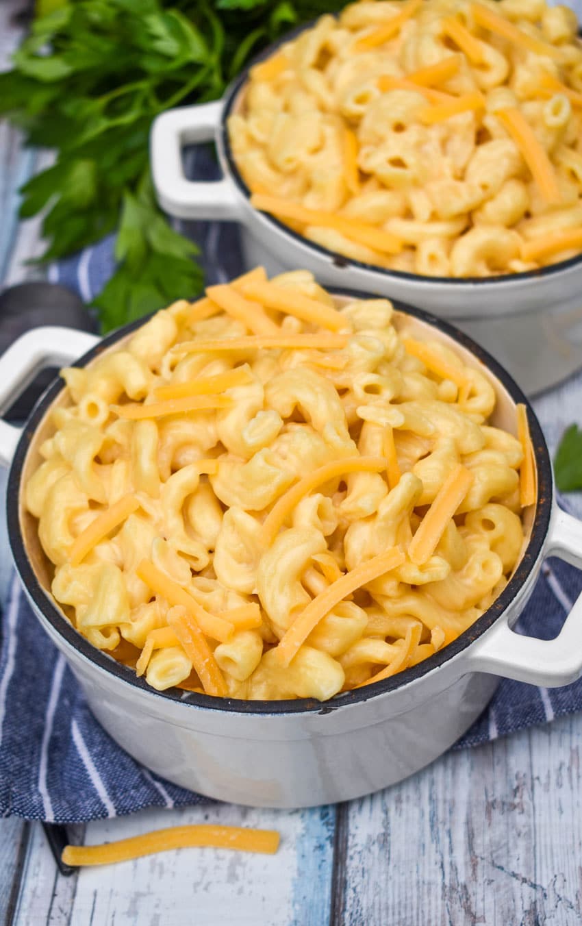 instant pot mac and cheese in two cast iron bowls topped with shredded cheddar cheese