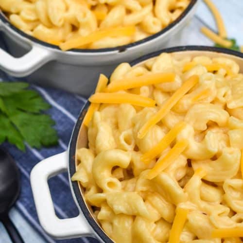 instant pot mac and cheese in two cast iron bowls topped with shredded cheddar cheese