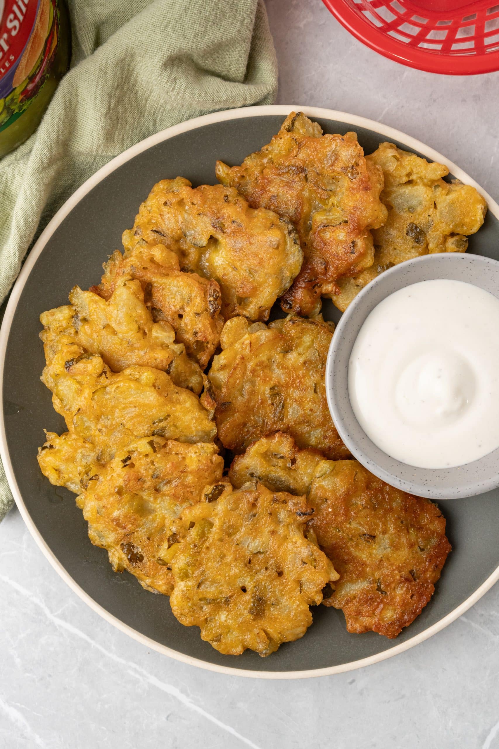 dill pickle fritters on a brown plate with a small gray cup filled with ranch dressing on the side