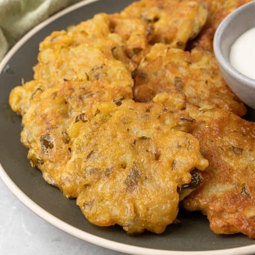 dill pickle fritters on a brown plate with a small gray cup filled with ranch dressing on the side