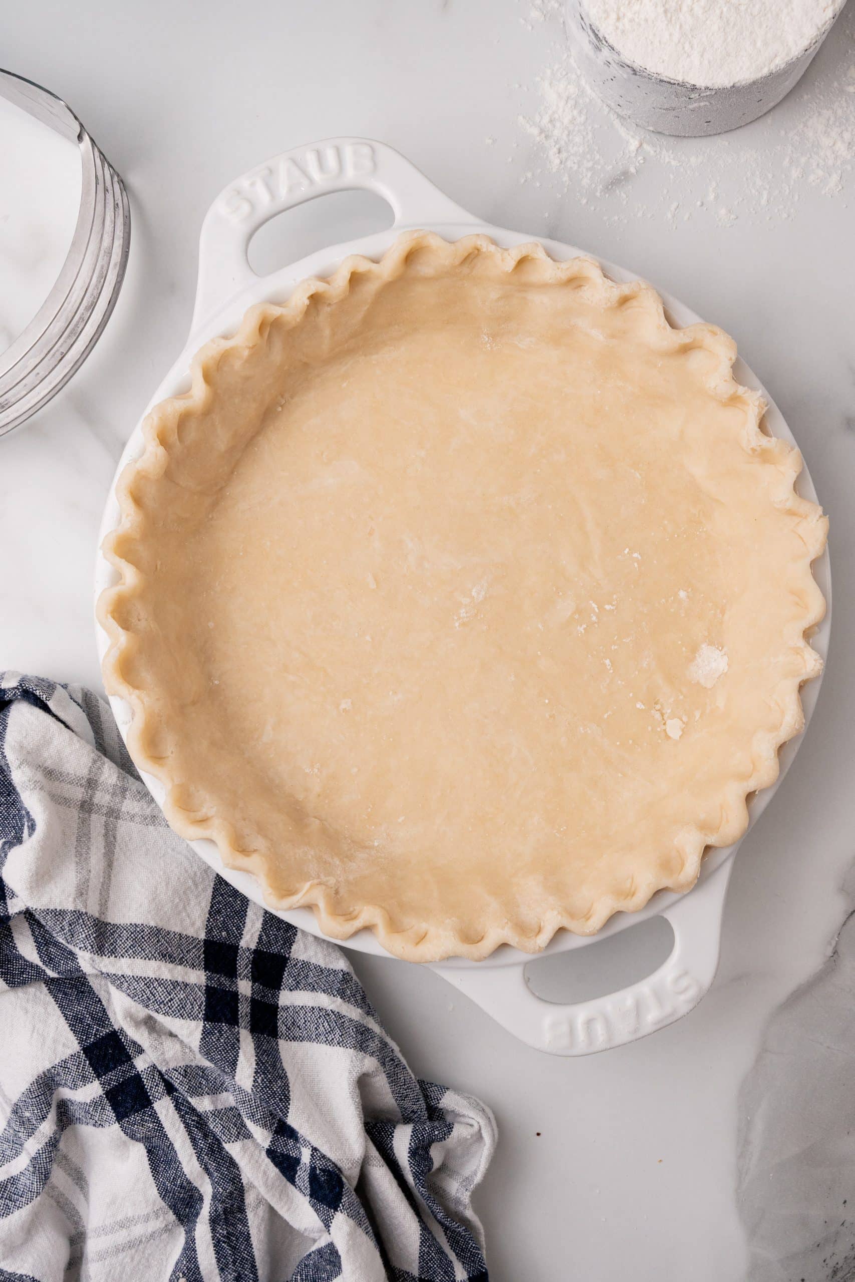 an unbaked easy homemade pie crust in a white pie dish with the edges crimped