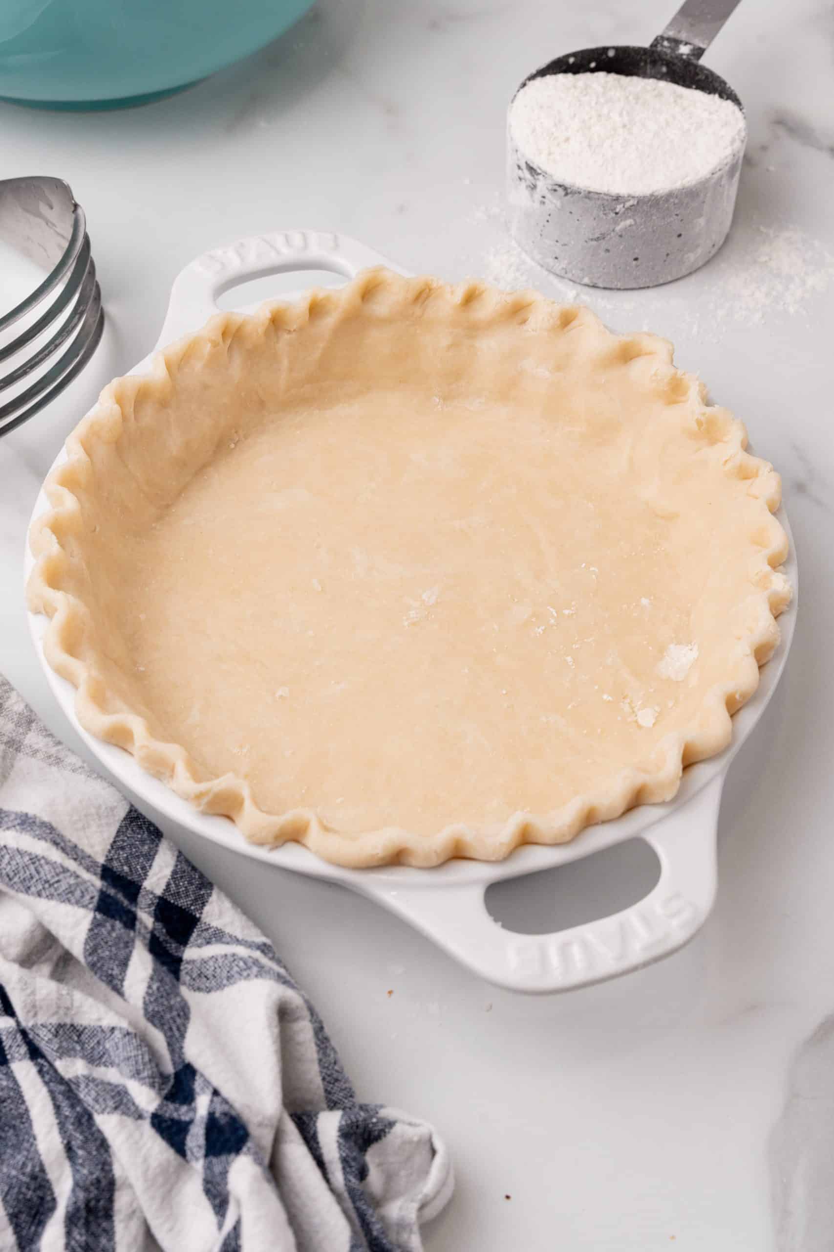 an unbaked easy homemade pie crust in a white pie dish with the edges crimped