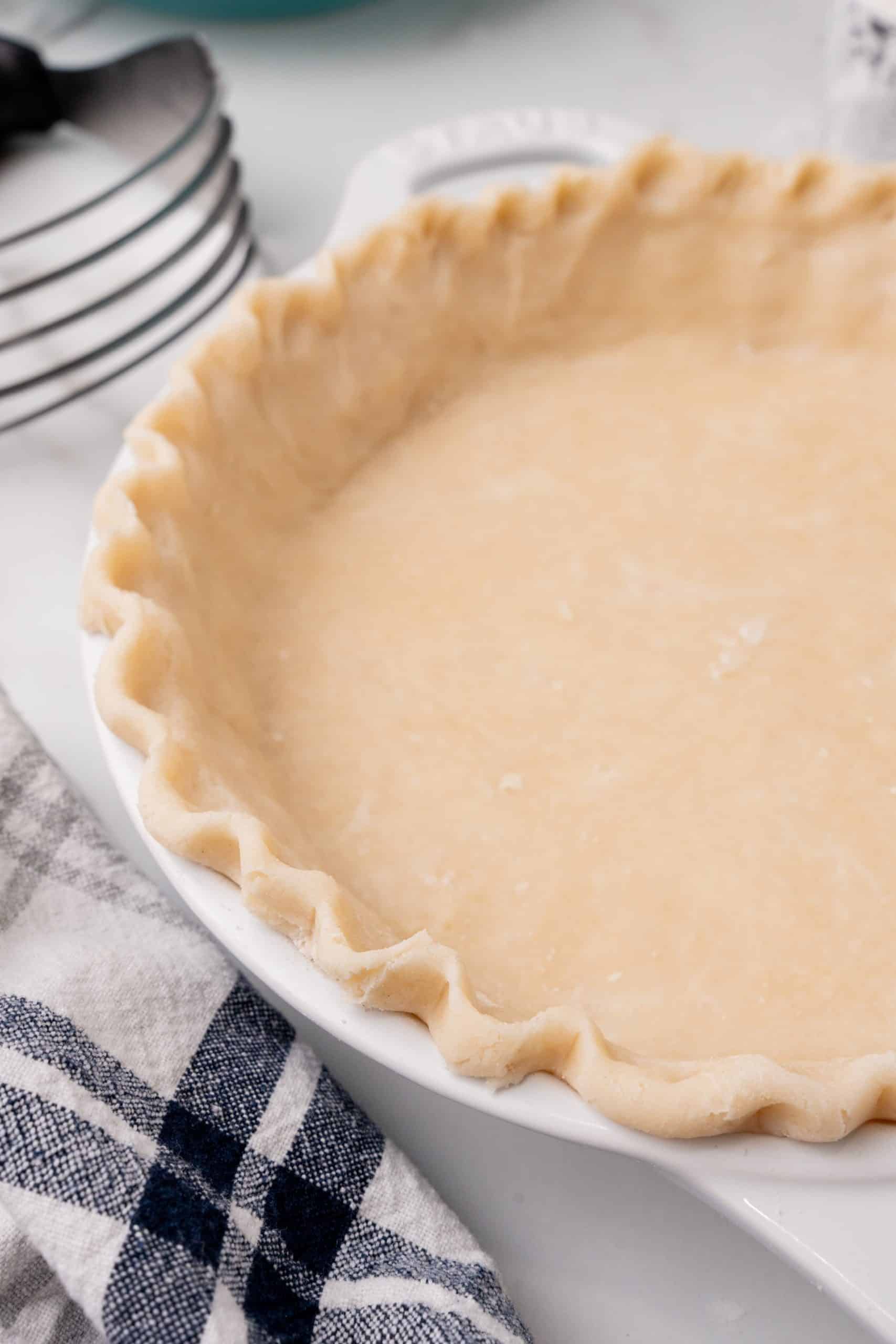 an unbaked easy homemade pie crust in a white pie dish with the edges crimped