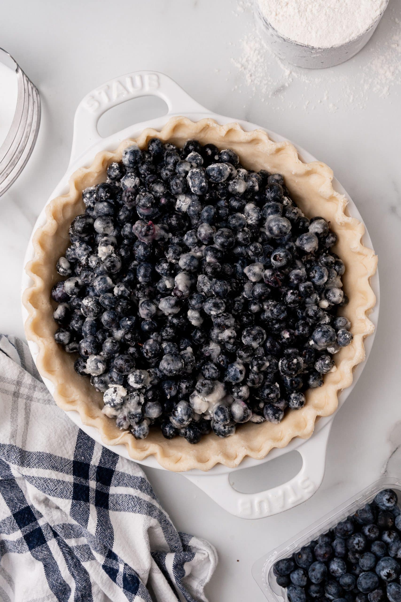 cornstarch coated blueberries in an unbaked easy pie crust in a white pie dish