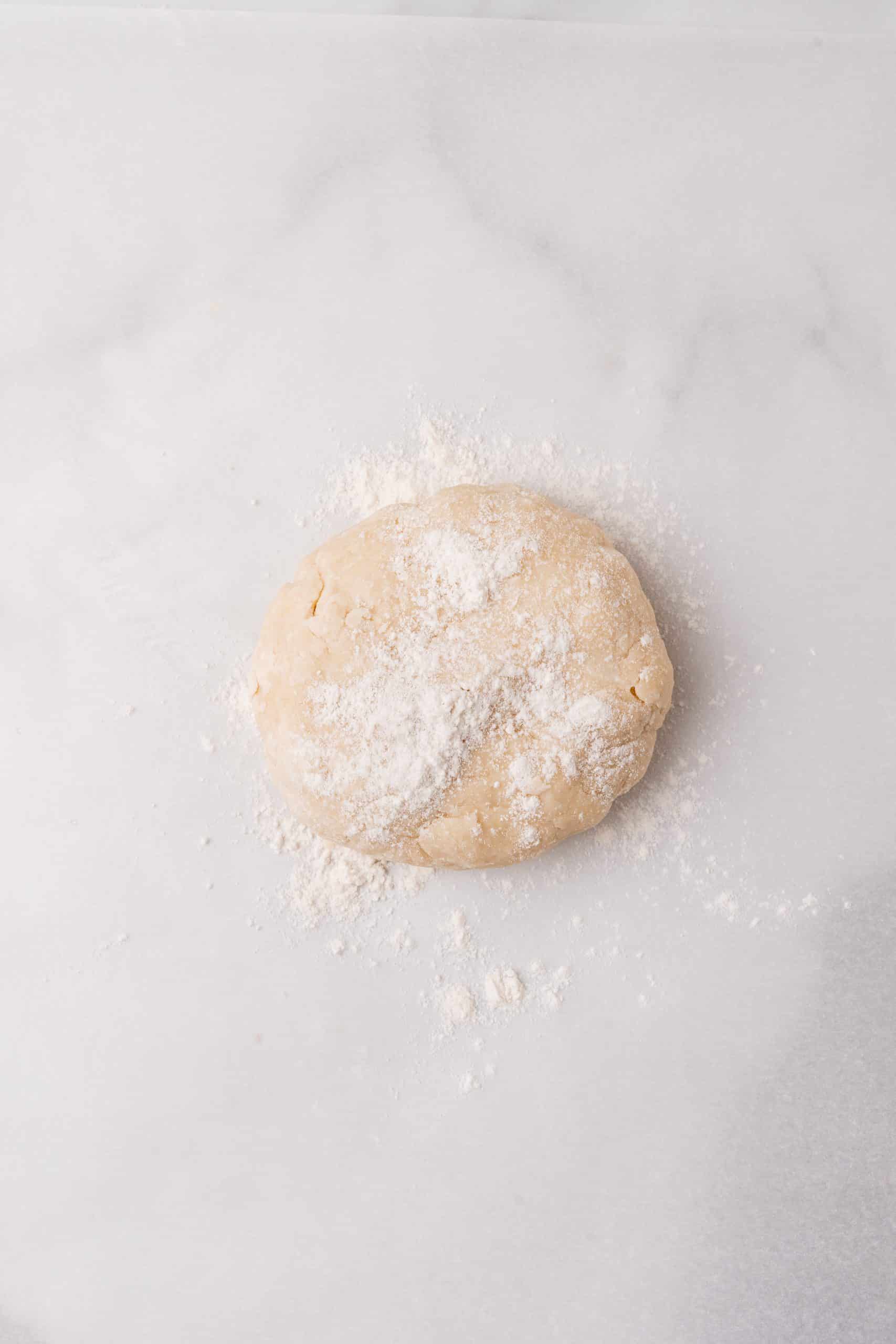 a floured ball of pie dough on a marble countertop