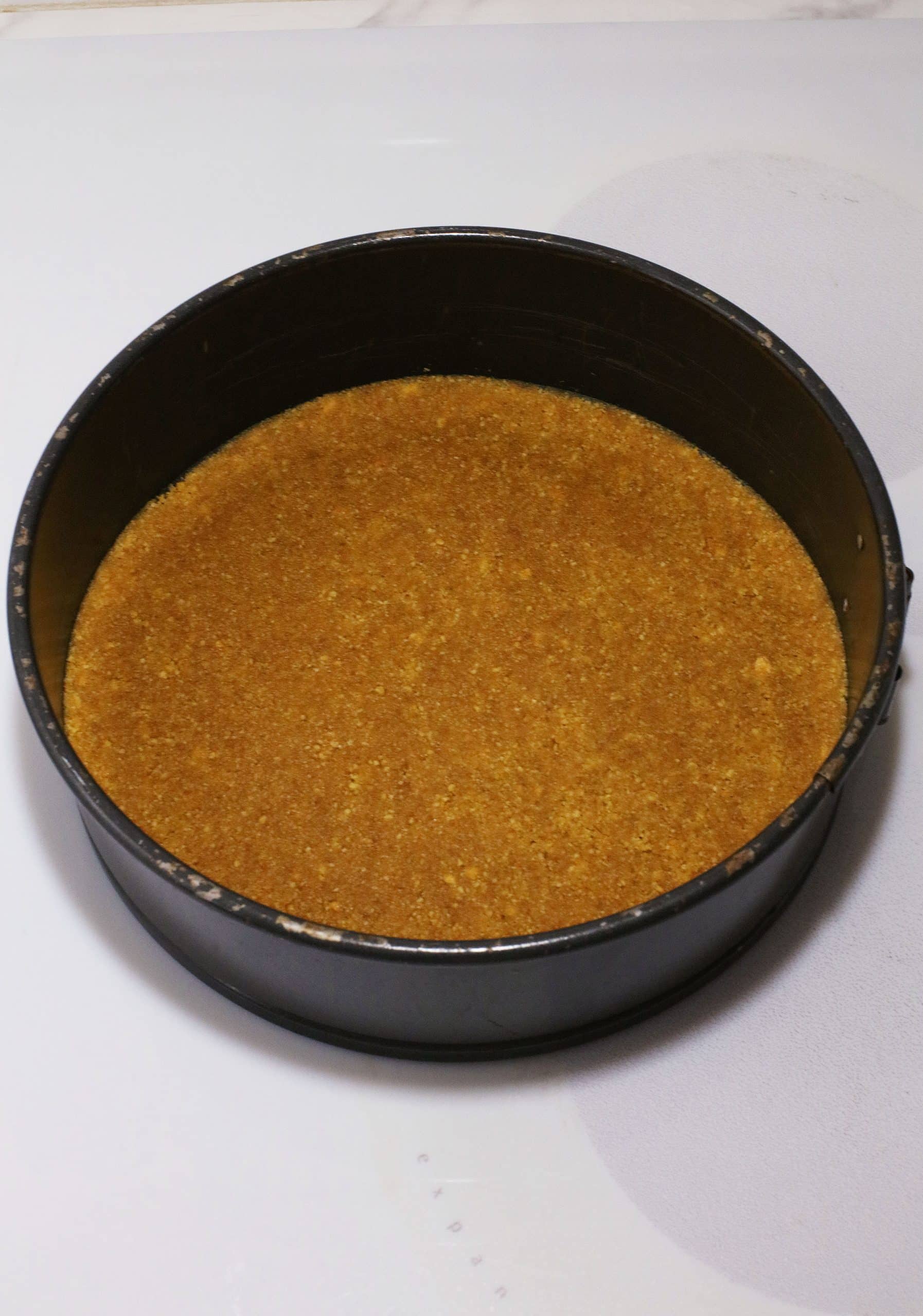 a graham cracker crust in a black springform pan