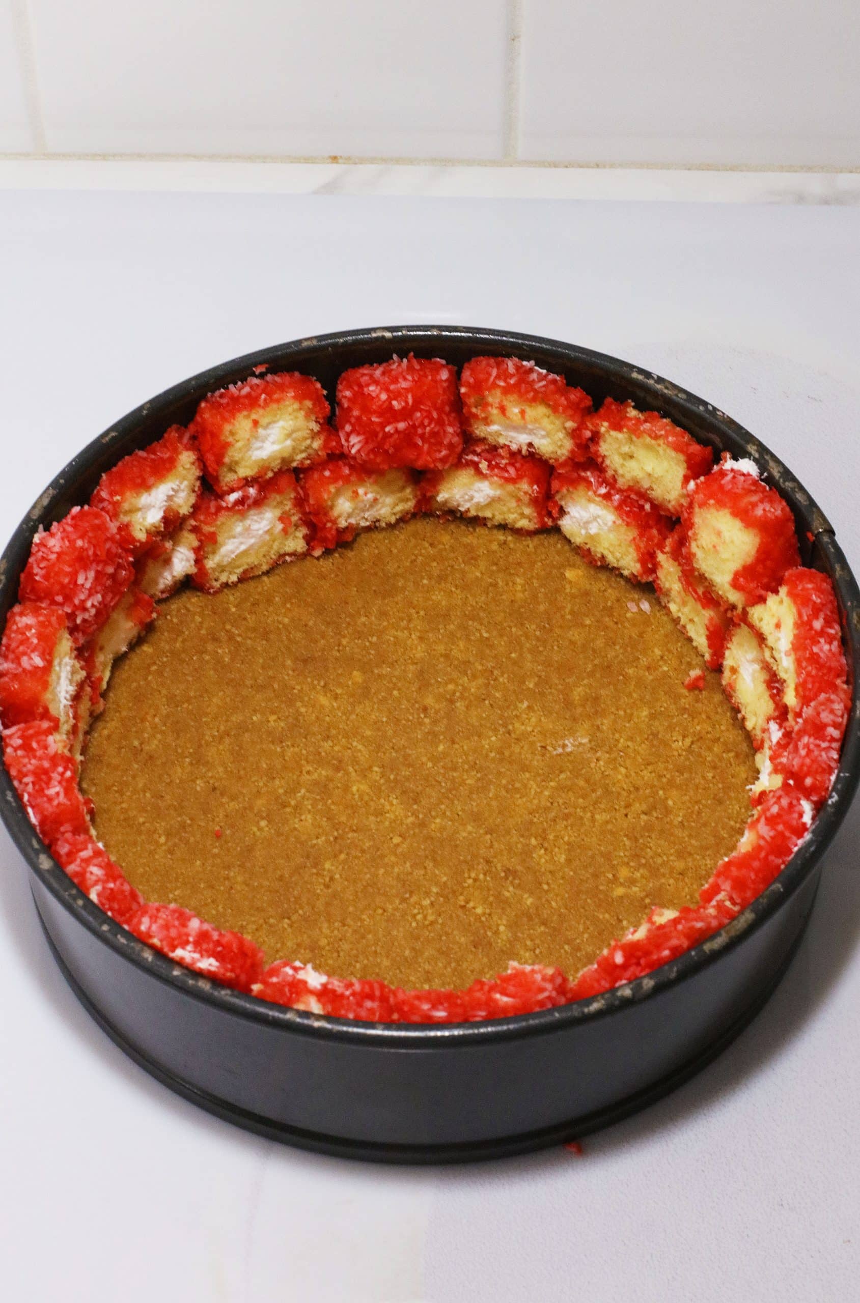 slices of raspberry zingers arranged on top of a graham cracker crust in a springform pan