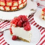 a slice of raspberry zinger cheesecake on a small white dessert plate with a silver fork on the side