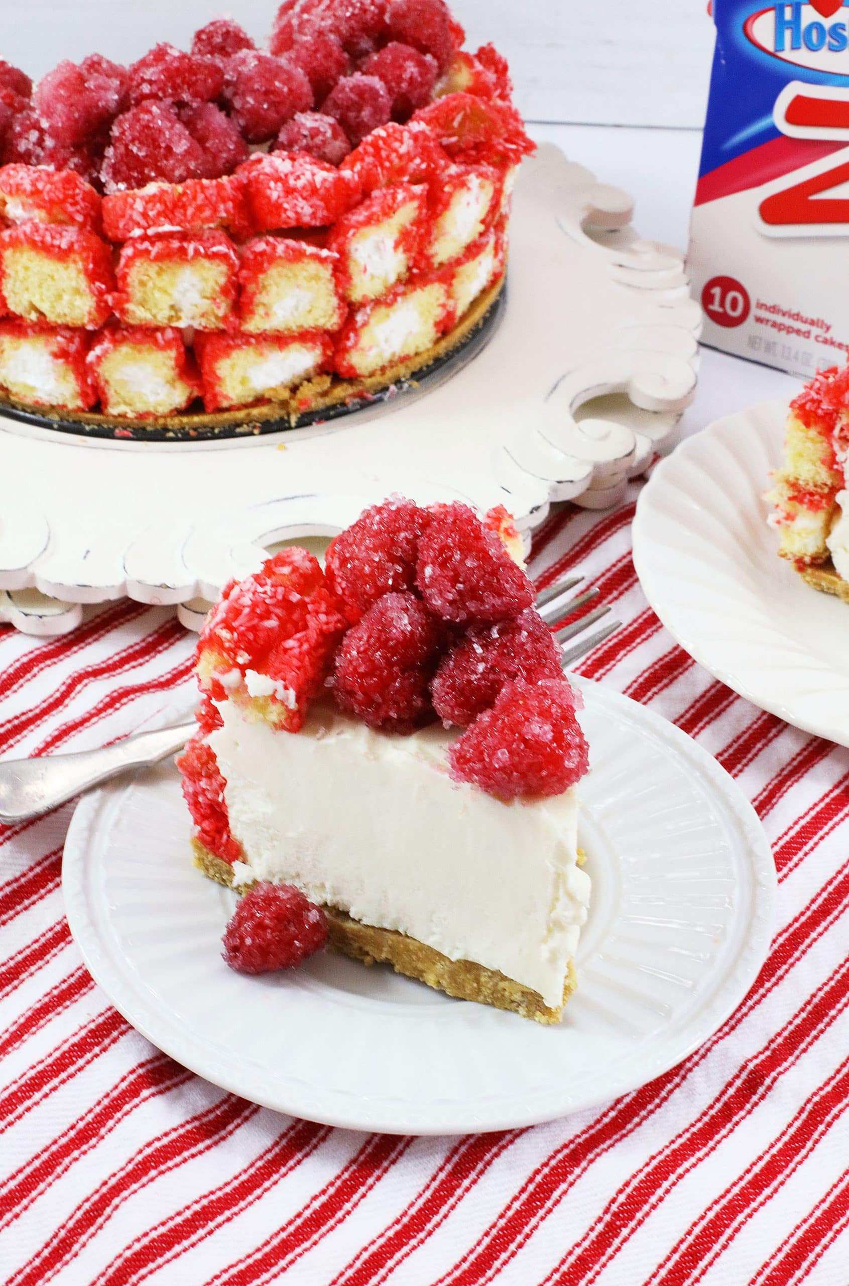 Raspberry Zinger Cheesecake a slice of raspberry zinger cheesecake on a small white dessert plate with a silver fork on the side