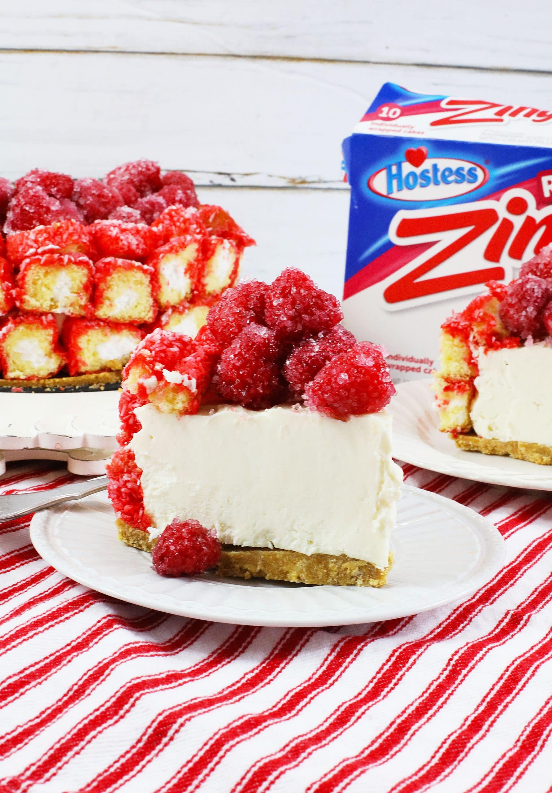 a slice of raspberry zinger cheesecake on a small white dessert plate with a silver fork on the side