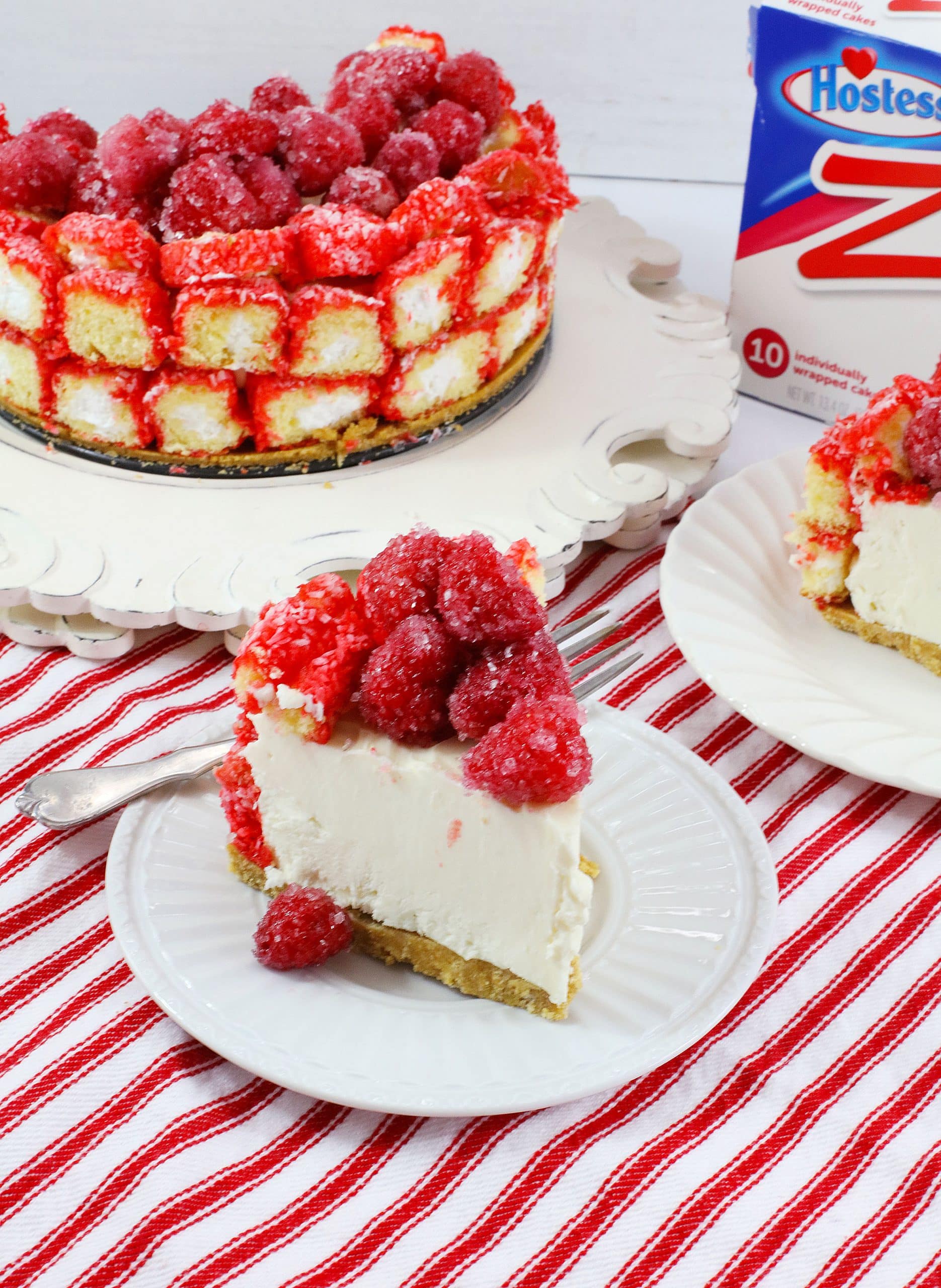 a slice of raspberry zinger cheesecake on a small white dessert plate with a silver fork on the side