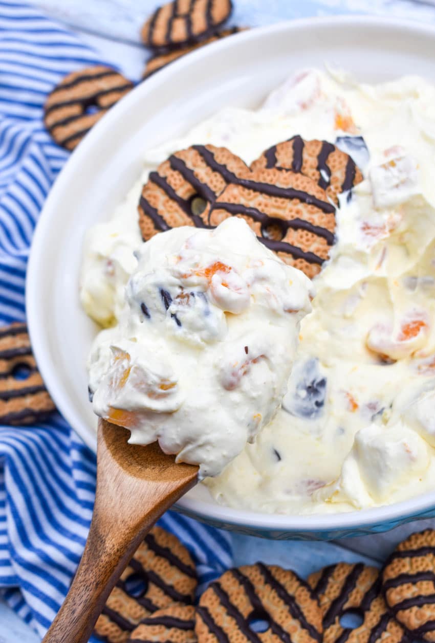 a wooden spoon scooping cookie salad out of a large serving bowl